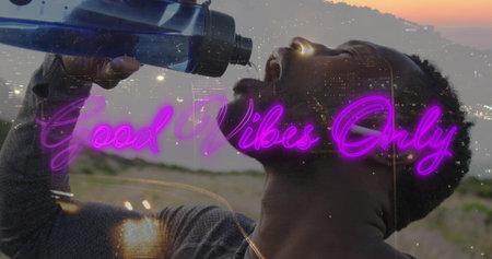 Tilting man in longsleeve shirt at sunset, drinking from blue sports bottle, neon. Outdoor, dusk, hydration, water, athletic, urban, doubleexposureの写真素材