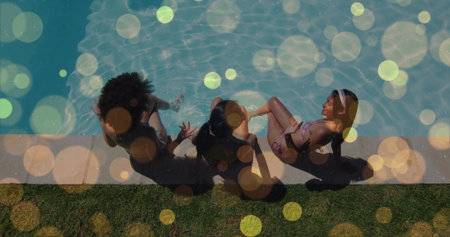 Sitting three women dangling feet on concrete pool edge at backyard, wearing swimsuits and headband. Outdoor, water, bokeh, friends, bikini, swimwear, relaxedの写真素材