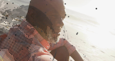 Sitting man facing glare on sandy shoreline, wearing striped shirt, showing halftone black speckles....