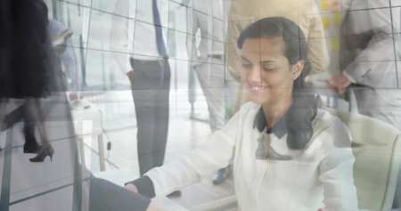Typing woman wearing white blouse seated at desk working on laptop in modern office, glass panels. Professional, collaboration, coworker, workspace, openplan, reflections, doubleexposureの写真素材