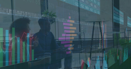 Talking team wearing business casual and blazer gesturing over overlay charts and laptop at office. Data, analytics, discussion, dashboards, silhouettes, modern, vibrantの写真素材