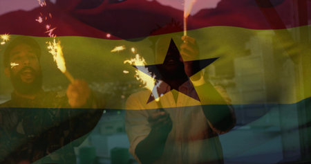 Holding lit sparklers, three adults waving on balcony at dusk, Ghana flag overlay, cap hoodie shirt. Friends, cityscape, night, celebration, sparks, glow, warmthの写真素材