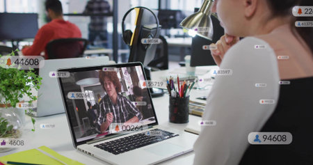 Watching female colleague viewing online call on laptop at open office, headset, badges, copy space. Workspace, collaboration, productivity, multimonitor, headphones, analytics, lampの写真素材