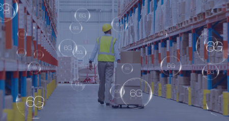 Walking warehouse worker wearing yellow hard hat hi-vis vest pulling pallet jack with boxes, 6G....