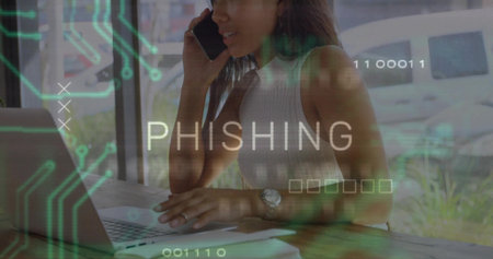 Talking woman wearing sleeveless top holding phone, typing on laptop at cafe windowの写真素材