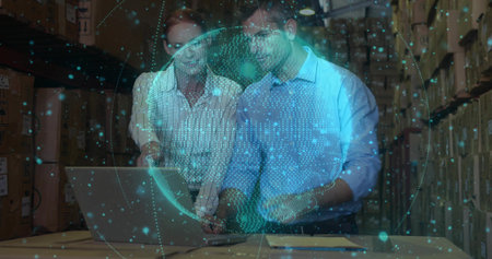 Two coworkers in business shirts reviewing laptop and papers in archive with data globe....
