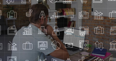 Resting chin midadult man wearing shirt specs viewing laptop phone at home office with icon overlay. Workspace, computer, notebook, glasses, finance, brick, plantの写真素材