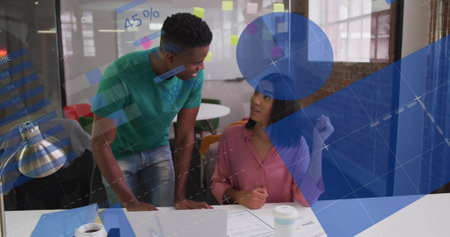 Leaning man in green tee, woman in pink blouse discussing documents with laptop data overlays. Collaboration, meeting, office, teamwork, planning, strategy, visualizationの写真素材