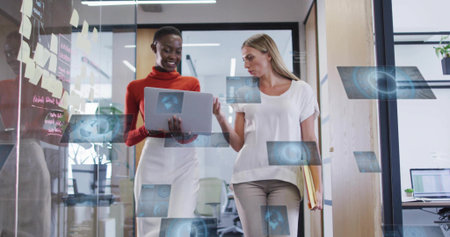 Walking two women in smart attire, holding laptop and files by sticky notes, office AR overlays. Coworkers, collaboration, teamwork, augmentedreality, holographic, minimalist, colorfulの写真素材