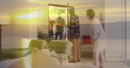 Greeting masked hosts and visitor holding bouquet at open front door in living room, warm sunlight. Guest, flowers, entryway, lounge, armchairs, plant, goldenhourの写真素材