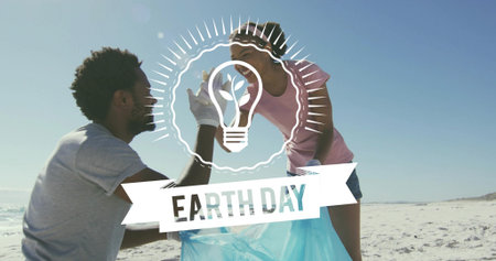 Collecting two volunteers wearing gloves on sandy beach, holding blue bag. Cleanup, coast, shoreline, teamwork, collaboration, seaside, oceanの写真素材