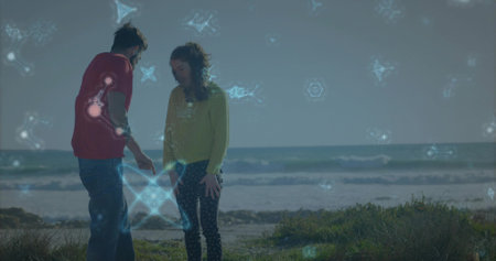 Pointing couple in red T-shirt and yellow sweater examining ground on coastal dune. Outdoor, beach,...