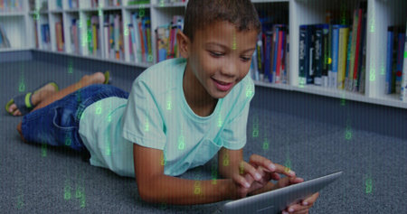 Lying boy wearing teal tee, dark jeans holding tablet, browsing in library with overlay. Child,...