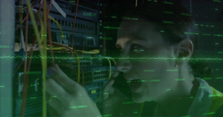 Fixing female tech wearing hi-vis vest, holding phone and rerouting Ethernet cables at server rack....