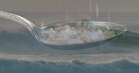 Floating metal spoon hovering above coastal shoreline, carrying coarse pink and white salt crystals....