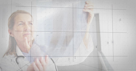 Examining senior clinician in white coat with stethoscope holding film in clinic, showing grid....