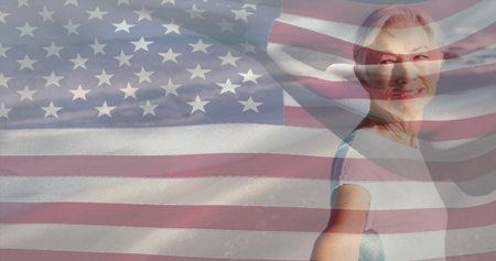 Smiling mature woman posing right in studio with short-sleeve top and US flag overlay, copy space. Patriotic, portrait, composite, backdrop, serene, stars, stripesの写真素材