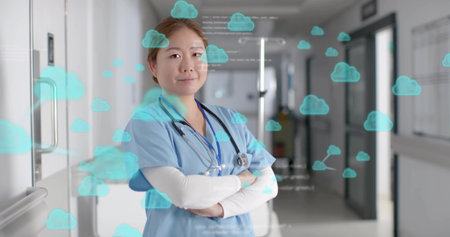Standing Korean nurse wearing blue scrubs and stethoscope in clinic hallway, showing cloud icons. Clinical, hospital, corridor, healthcare, digital, visualization, calmの写真素材