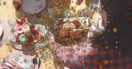 Placing host in red-blue plaid shirt arranging roasted whole bird on home table, with candles....