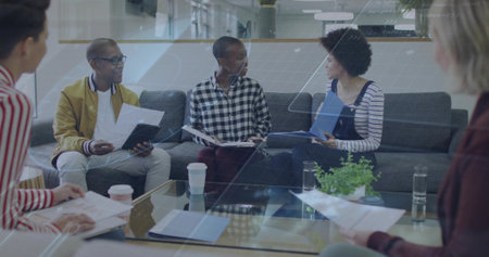 Discussing papers, five coworkers in smart casual holding blue folder and tablet in office lounge....