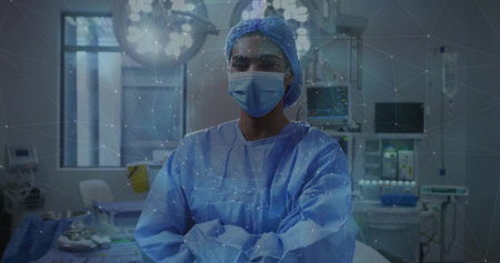 Standing female surgeon in blue gown and mask, crossing arms in operating theater with digital mesh....