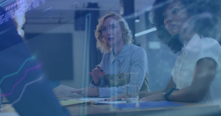 Speaking blonde woman in striped top and colleague in white blouse gesturing at table, laptop data....