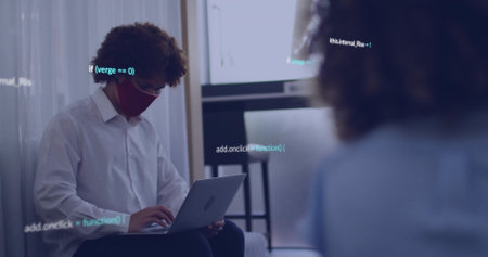 Typing man wearing white shirt and red mask on sofa in office, laptop with code overlay....