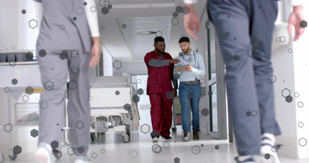 Walking men in scrubs and blue shirt with stethoscope examining tablet in hospital corridor gurney....