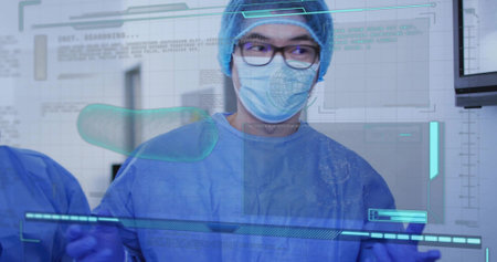Viewing mature male clinician in blue surgical PPE studying holographic overlays in surgical suite....