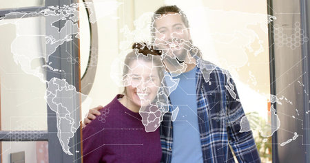 Posing couple smiling embracing at front door wearing plaid shirt and purple knit world map overlay....