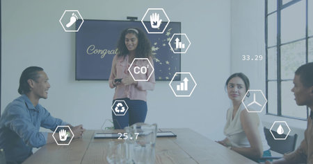 Leading woman in pink top holding remote, briefing team at conference table with hexagonal icons. Presenter, boardroom, meeting, collaboration, sustainability, infographic, analyticsの写真素材