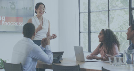 Presenting woman wearing white blouse and dark bottoms gesturing in conference room with monitor. Presenter, meeting, boardroom, office, collaboration, teamwork, leadershipの写真素材