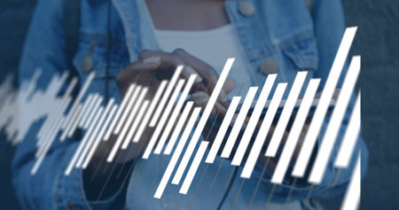 Holding smartphone, woman tapping screen at gray wall, denim jacket shoulder strap waveform. Phone, closeup, urban, data, focus, texture, bagの写真素材