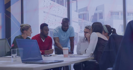 Discussing six colleagues leaning around meeting table, reviewing laptop papers in business attire. Conference, collaboration, teamwork, office, modern, bright, windowsの写真素材