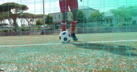 Standing soccer player wearing red kit, controlling ball on marked pitch with cyan grid overlay. Football, field, turf, goal, jersey, augmented, realityの写真素材