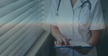 Writing nurse by window, white coat stethoscope blue clipboard pen blinds windowsill, copy space. Physician, professional, realistic, medical, clinic, notes, documentationの写真素材