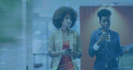 Walking two coworkers in office hall in blazer, denim, holding phone, cup, folder, showing charts. Colleagues, collaboration, analytics, graphs, data, corporate, modernの写真素材