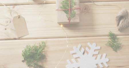Displaying white felt snowflake ornament on light wood table, with kraft gift, twine, fairy lights. Flatlay, holiday, rustic, cozy, warm, glow, naturalの写真素材