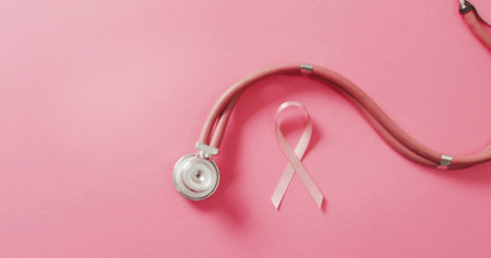 Displaying pink stethoscope and awareness ribbon lying on pastel pink surface, silver chest piece. Health, medical, studio, flatlay, branding, campaign, wellnessの写真素材
