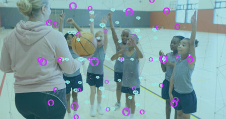 Holding basketball, coach directing children at school gym, in pink hoodie, purple teal overlay. Drills, practice, youth, teamwork, court, gymnasium, studentsの写真素材