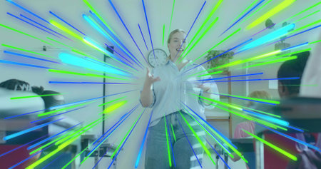 Showing teacher holding analog clock and papers at front of class with desks, board, radial overlay. Educator, students, classroom, plants, materials, vibrant, colorfulの写真素材