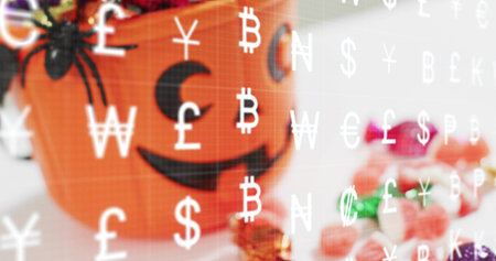 Displaying orange jackolantern sitting left on tabletop spider candies and cash overlay, copy space. Pumpkin, arachnid, candy, chocolates, currency, glyphs, patternの写真素材