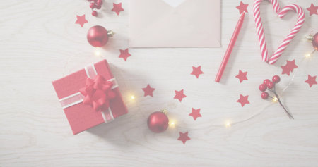 Displaying red box with white ribbon and bow on pale wood tabletop, featuring candy cane heart. Flatlay, festive, confetti, lights, envelope, pink, textureの写真素材