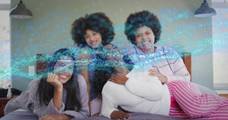 Reclining four women wearing pajamas and loungewear on bed in bedroom, with blue overlay. Family, bonding, together, cozy, intimate, relaxation, homeの写真素材
