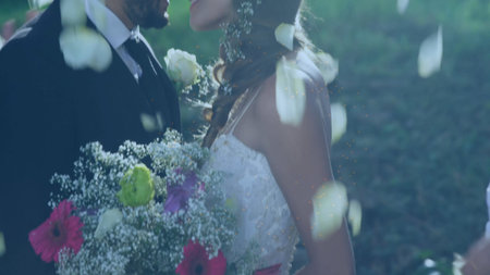 Bride and groom are leaning into kiss in flat design wedding, featuring bouquet and falling petals. Romance, celebration, elegance, natural, floral, intimacy, joyの写真素材