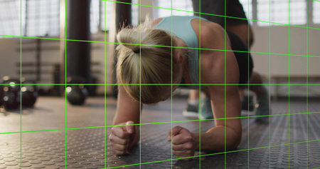 Holding woman holding forearm plank on rubber floor with kettlebells, wearing blue top and shorts. Gym, training, partner, workout, daylight, windows, studioの写真素材