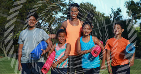 Smiling woman wearing orange tank top leading four children in park, holding blue red pink mats. Group, coach, female, outdoors, fitness, yoga, minorsの写真素材