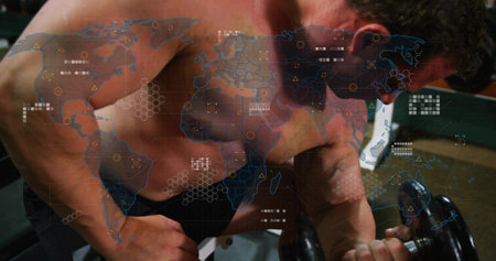 Lifting muscular shirtless man curling heavy dumbbell over bench at gym, with world map overlay....