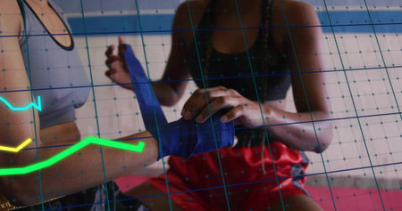 Wrapping two female athletes' hands in boxing gym, with blue wrap, sports bras, red shorts....
