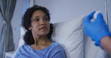 Watching woman propping on hospital bed in light blue top, gloved hand holding syringe, copy space....